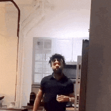 a man in a black shirt is standing in a kitchen with a cigarette in his mouth