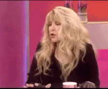 a woman with blonde hair is sitting at a table