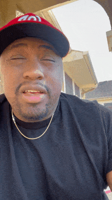 a man wearing a black shirt and a red hat with the letter s on it