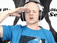a bald man wearing headphones salutes in front of a sign that says old sea