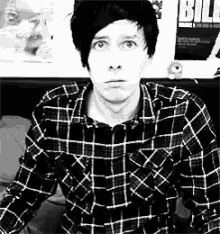 a black and white photo of a man wearing a plaid shirt and a blurry background