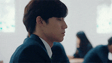 a man in a suit is sitting in a classroom with his eyes closed .