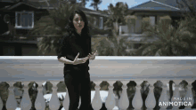 a woman is standing on a balcony with the words made in animatica visible
