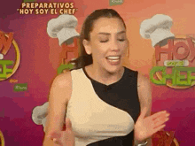 a woman in a black and white dress is standing in front of a chef 's hat .