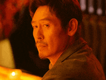 a close up of a man 's face with a candle in the foreground