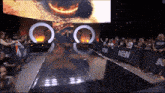 a crowd of people watching a wrestler on a stage with a aew banner