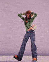 a girl wearing headphones and a green sweater stands in front of a purple background