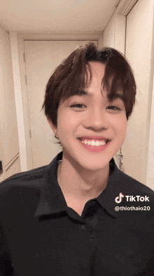 a young man wearing a black shirt is smiling for the camera and has a tiktok account