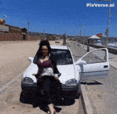 a woman is standing next to a white car with pixverse.ai written on the bottom