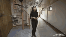 a woman stands in a hallway with a spiral staircase in the background and the words made in animotica on the bottom