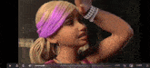 a barbie doll is wearing a purple headband and earrings and holding her head .