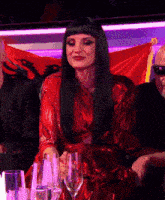 a woman in a red dress sits at a table with glasses of water