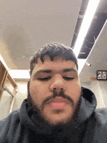 a man with a beard is wearing a black hoodie and looking at the camera