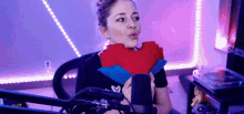 a woman is holding a stuffed heart in front of a microphone