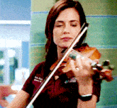a woman playing a violin wearing a maroon shirt that says ' uc san diego ' on it