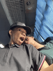 a man wearing a hat with the letter d on it is laying next to another man