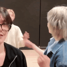 a woman wearing glasses is holding a child 's hand while standing next to another woman .
