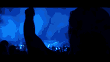 a man playing drums in a dark room with a blue light behind him
