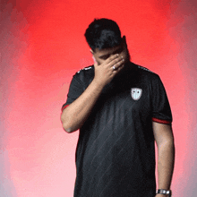 a man wearing a black shirt with the letter tp on it covering his face