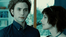 a man and a woman are looking at each other in front of a bookshelf