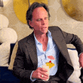 a man in a suit is holding a drink with an umbrella on top