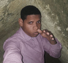 a man in a pink shirt holds his nose
