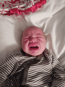 a baby in a striped outfit is crying