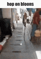 a group of people are walking down a sidewalk with the words `` hop on bloons '' on the bottom .
