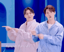 two men are pointing at something with a blue background and a foreign language written on the bottom