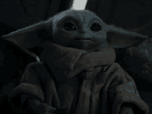 a baby yoda is wearing a scarf around its neck