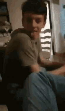 a young man sitting down with his tongue out