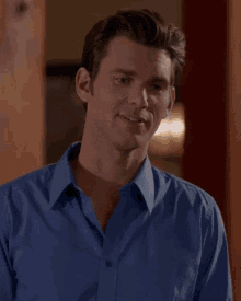 a man in a blue shirt is smiling and looking to the side