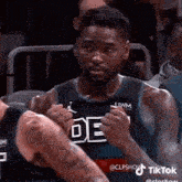 a basketball player is sitting in the stands during a game and making a funny face .