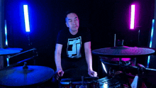 a man in a black shirt with the letter j on it playing drums