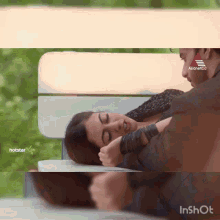 a man and a woman are laying on a bench with a hotstar logo in the background