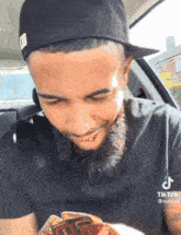 a man with a beard is wearing a hat and looking at a card that says tiktok