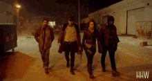 a group of people walking down a street with the letters hw on the bottom right
