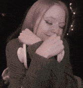 a woman wearing a green sweater is smiling with her hands on her face