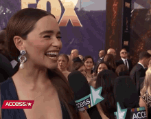 a woman in a blue dress is smiling while being interviewed by access
