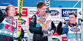 a group of skiers are standing on a stage and one of them has a trophy in his hand