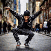 a man in a leather jacket is kneeling down on the street .