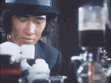 a man in a hat is pouring a cup of coffee into a cup .