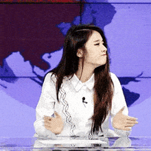 a woman sitting at a desk with her hands outstretched