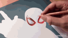 a person is drawing a spiderman with a red pencil on a piece of paper .