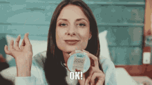 a woman is holding a container that says ok