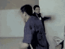a blurry picture of a man in a blue shirt standing next to another man