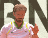 a man with a beard wears a white shirt with a lacoste logo on it