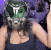 a woman wearing a helmet with a green face painted on it holds a gun