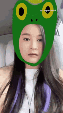 a girl wearing a green frog hat with the words " in your area " on the bottom