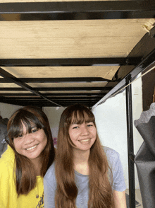two girls standing under a bunk bed with one wearing a shirt that says ' california ' on it